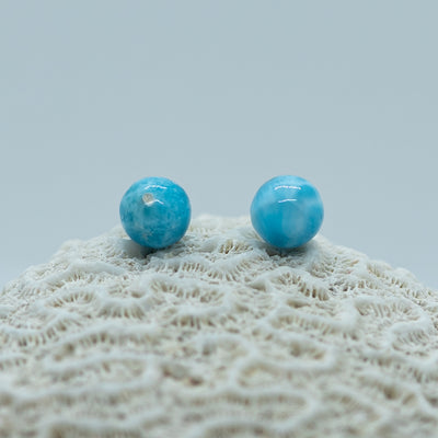 Deux perles de larimar d'un bleu puissant posées sur un coquillage. Le larimar est de couleur bleu et c'est une pierre naturelle se trouvant en République Dominicaine.