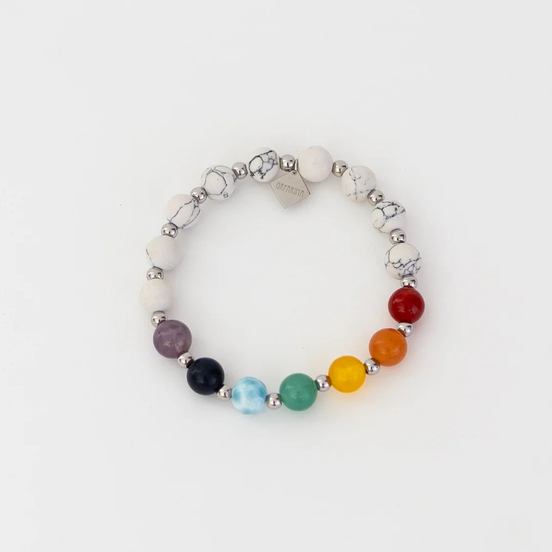 Bracelet en holite avec sept pierre de couleur différentes représentant les sept chakras. Bracelet avec une breloque en acier inoxydable 316L orparima.